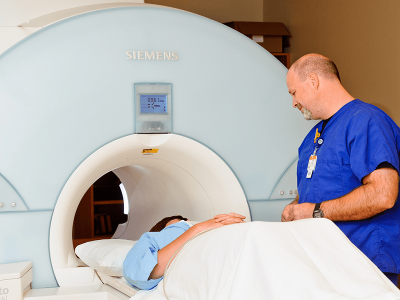 Photo of tech with patient getting MRI